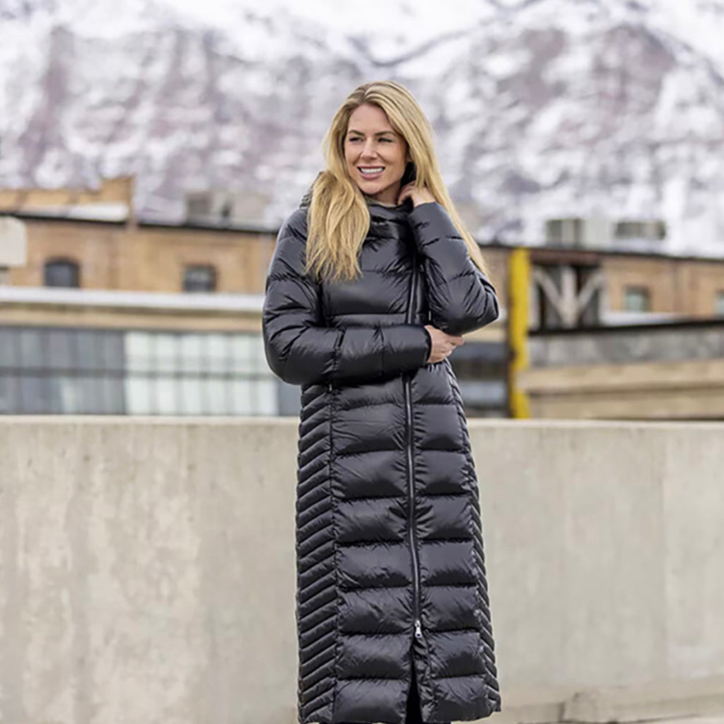 En Jakke, Alina Long Coat i farven sort set på en kvinde med bjerge i baggrunden